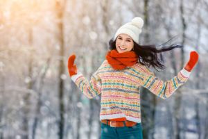 Frau hüpft draußen im Winter und freut sich, dass sie so fit ist.