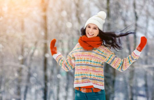 Frau hüpft draußen im Winter und freut sich, dass sie so fit ist.