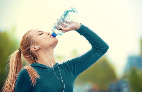 Joggerin trinkt Wasser aus PET-Flasche.