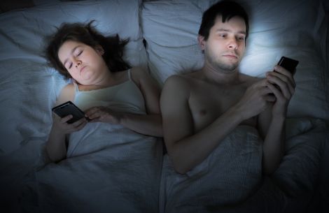 Alles ist dunkel, nur das Gesicht wird vom Smartphone beleuchtet und hält so das Gehirn im Wachmodus.