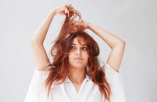Portrait einer Frau, die ihre Haare nach oben zieht.