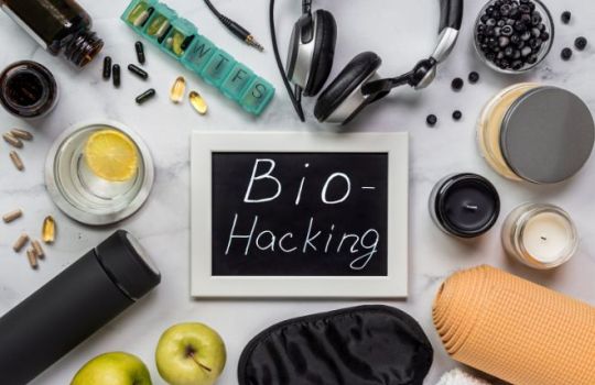 Fotografie einer Ansammlung diverser Gegenstände, die im Biohacking eine Rolle spielen, das Wort 'biohacking' auf einer Schiefertafel