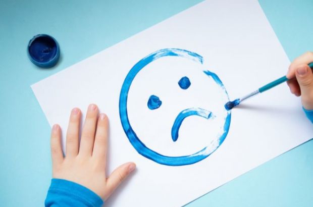 Manche Kinder müssen leider schon früh erfahren, was Depressionen sind. © Изображения пользователя Anastasiia Bidzilia, canva pro Kinderhände malen einen blauen, traurigen Smiley auf ein Blatt Papier