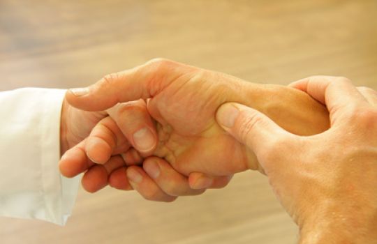 Arzt untersucht Hand- und Fingergelenke eines Rheumapatienten.