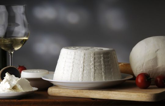 Ricotta auf einem Teller, angerichtet auf einem Holzbrett.