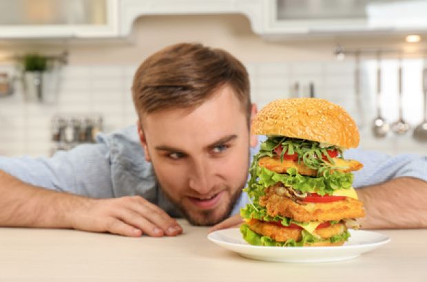 Besonders säurelastig sind Käse, Eier, Fisch und Fleisch, aber auch verschiedene Getreideprodukte. © New Africa - Fotolia.com Junger Mann liebäugelt mit einem riesigen Burger.