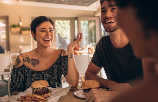 Freunde in einem Restaurant, die vergnügt Burger essen.