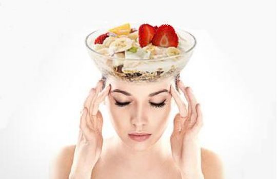 Frau mit Kopfschmerzen und Müsli